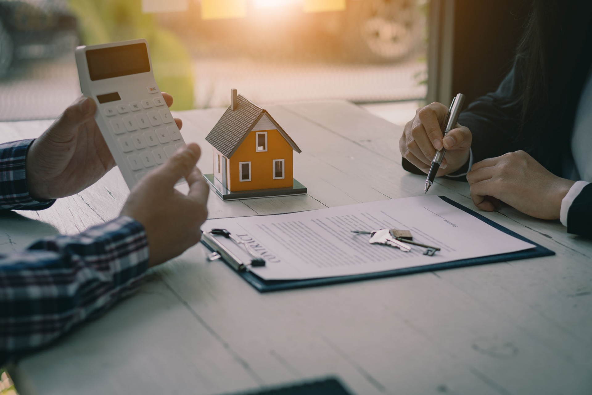 Real estate professionals offer their clients contracts to discuss home purchases, insurance or real estate loans. Home sales agents sit at the office with new home buyers in the office.